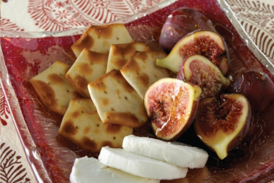 Red plate with crackers and fresh figs and cheese 